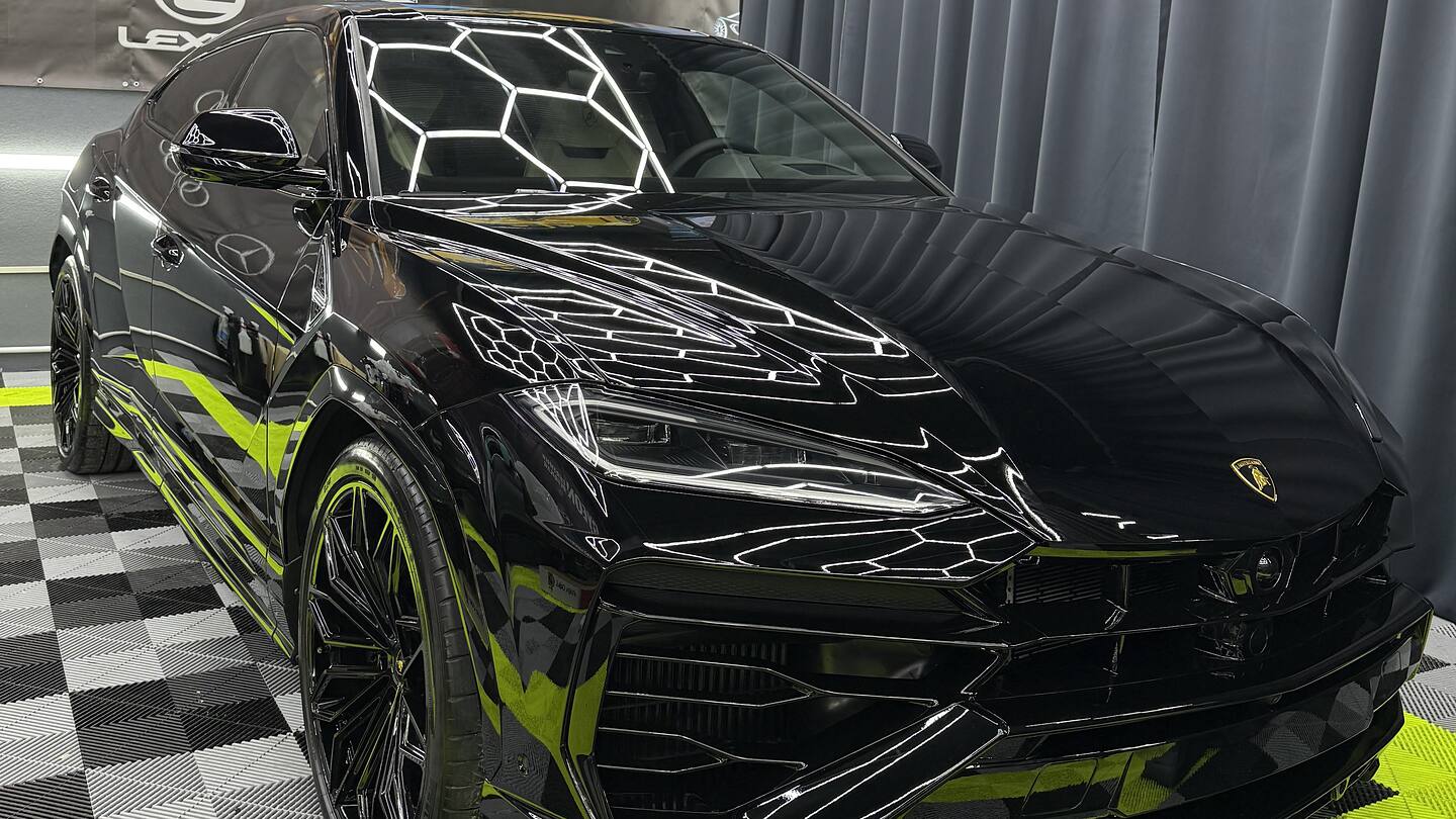 Lamborghini Urus negru în atelierul Imperial Detailing, cu reflexiile plafonului hexagonal pe capota corectată