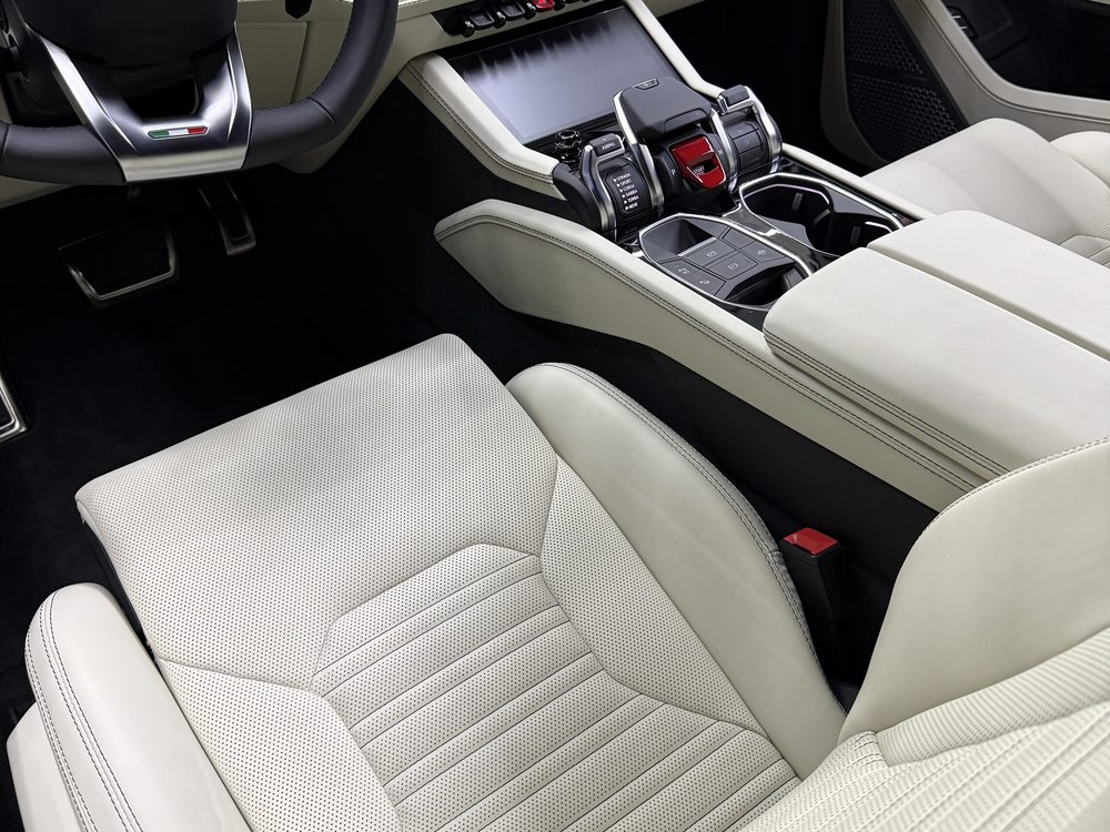 Interior de Lamborghini Urus cu piele albă, scaunele față și consola centrală curățate complet