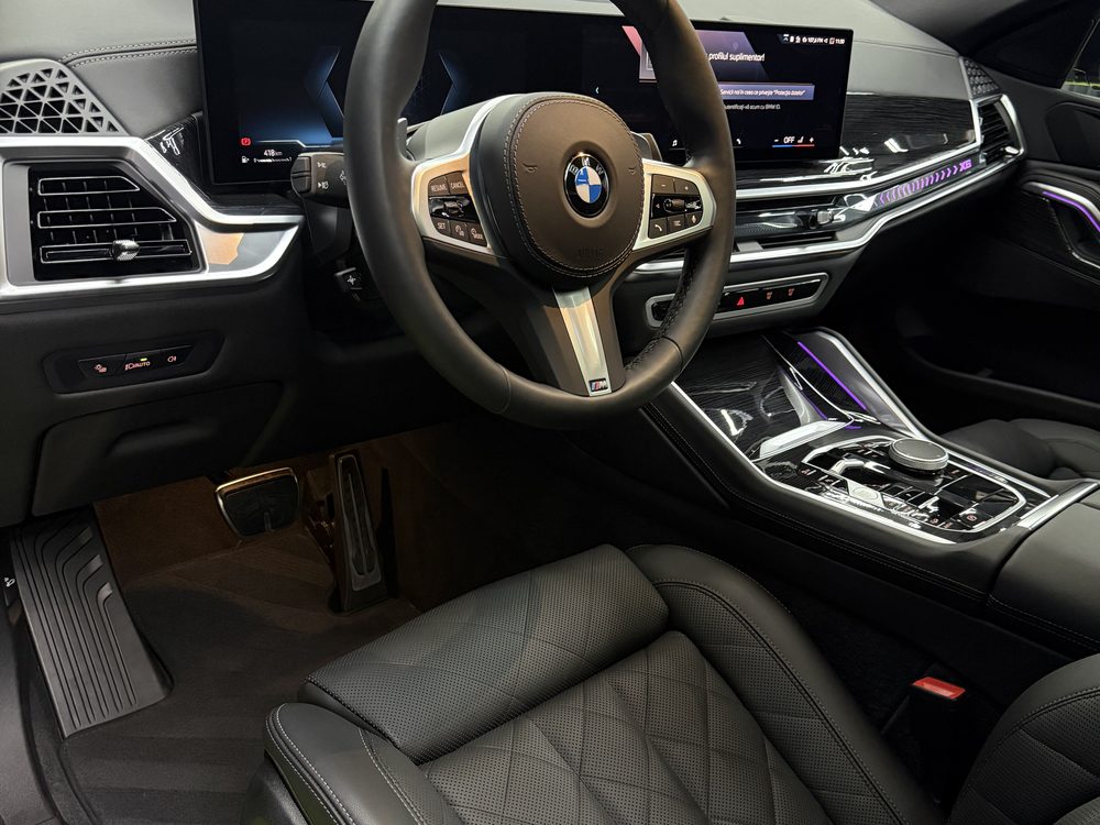 Bord, volan și scaun din piele neagră matlasată într-un BMW, cu grilele și butoanele fără praf încrustat
