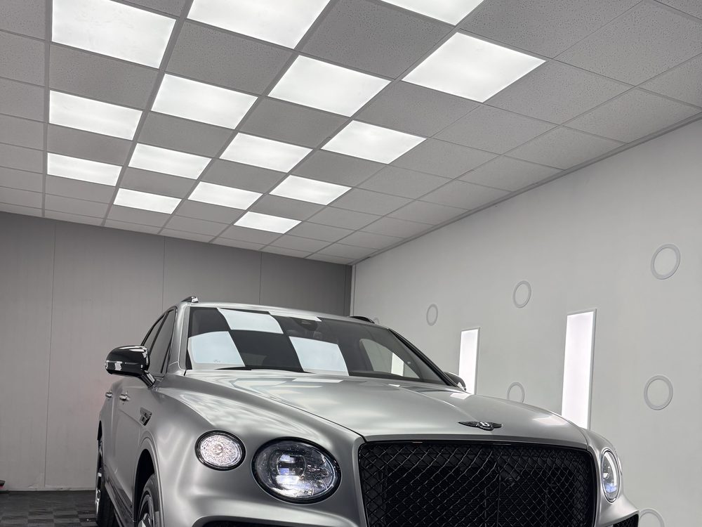 Bentley Bentayga gri-argintiu, văzut din față-stânga, pe podea în carouri