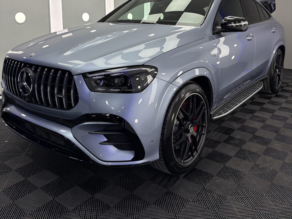 SUV coupé Mercedes-Benz gri-argintiu, văzut din față-stânga, cu grilă cu lamele verticale și jante negre