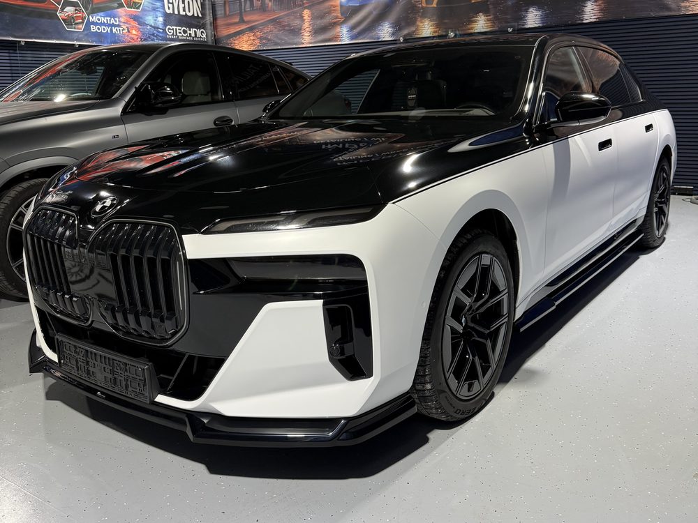 BMW berlină lungă în două tonuri, negru peste alb, văzut din față-stânga, cu grilă verticală iluminată