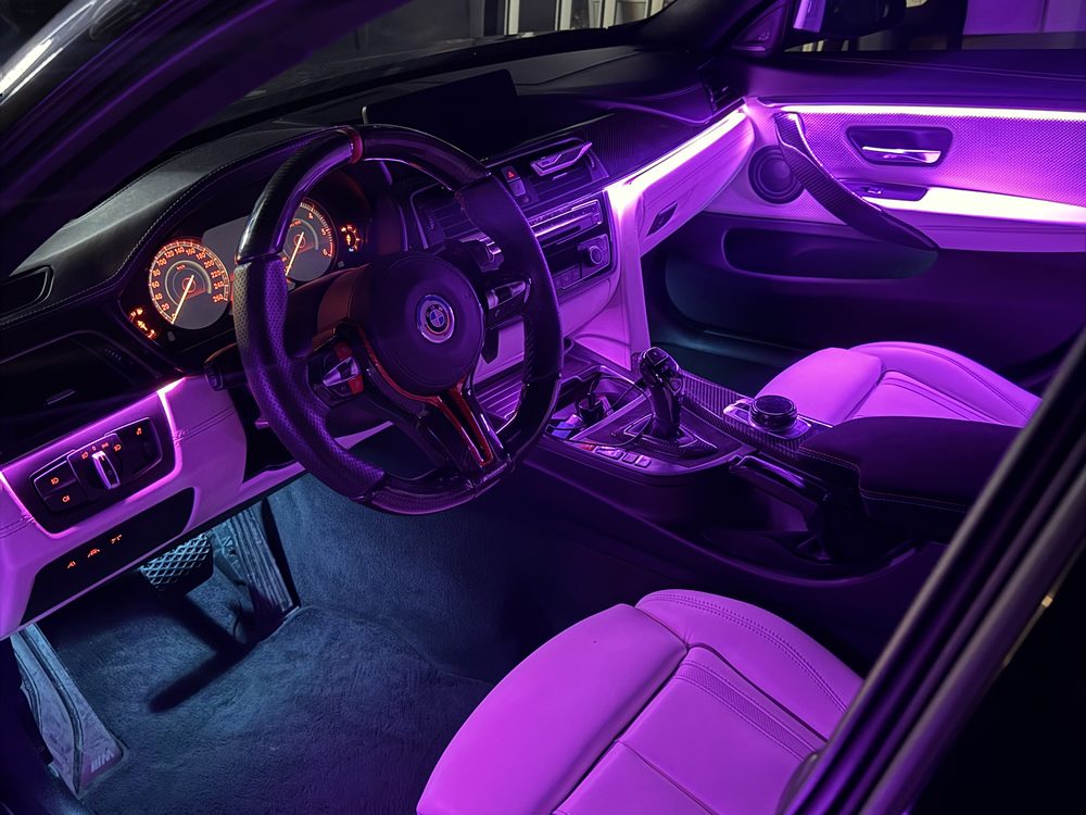 Interior auto iluminat în mov, cu linii luminoase pe bord și portiere și lumină în zona picioarelor