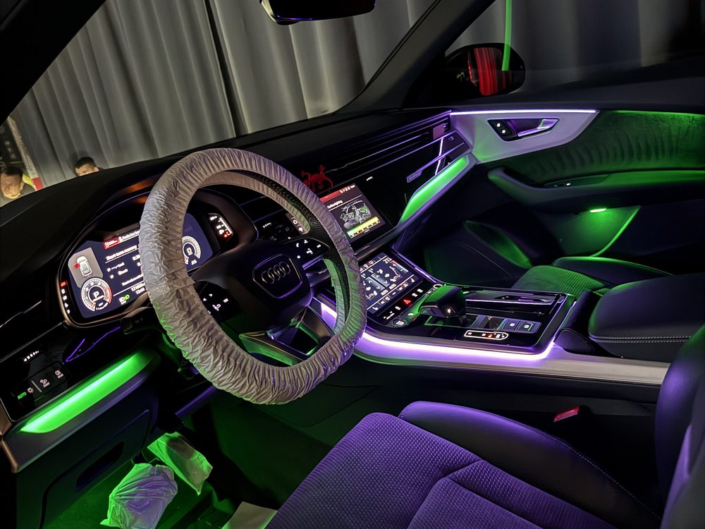 Interior auto iluminat verde pe bord, consola centrală, portieră și zona picioarelor