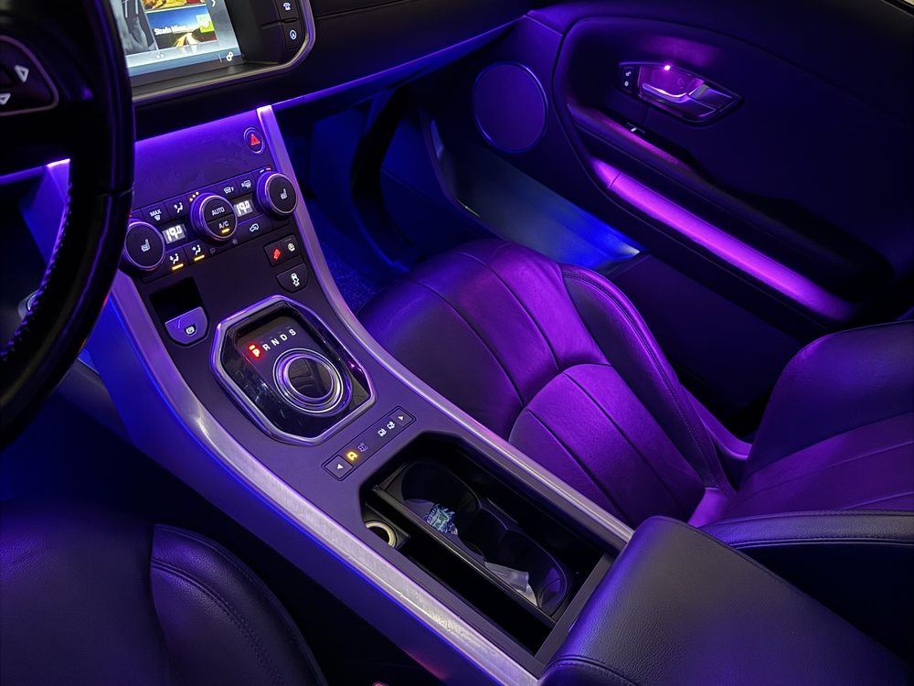 Consolă centrală și portieră auto iluminate în mov și albastru