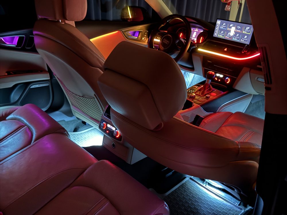Interior auto văzut dintre scaunele din spate, iluminat în roșu, albastru și alb