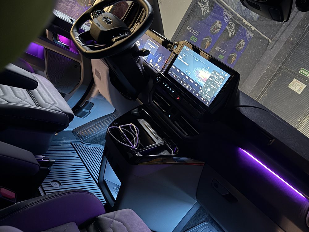 Interior auto cu ecrane centrale și linie de lumină mov integrată în bord și portieră